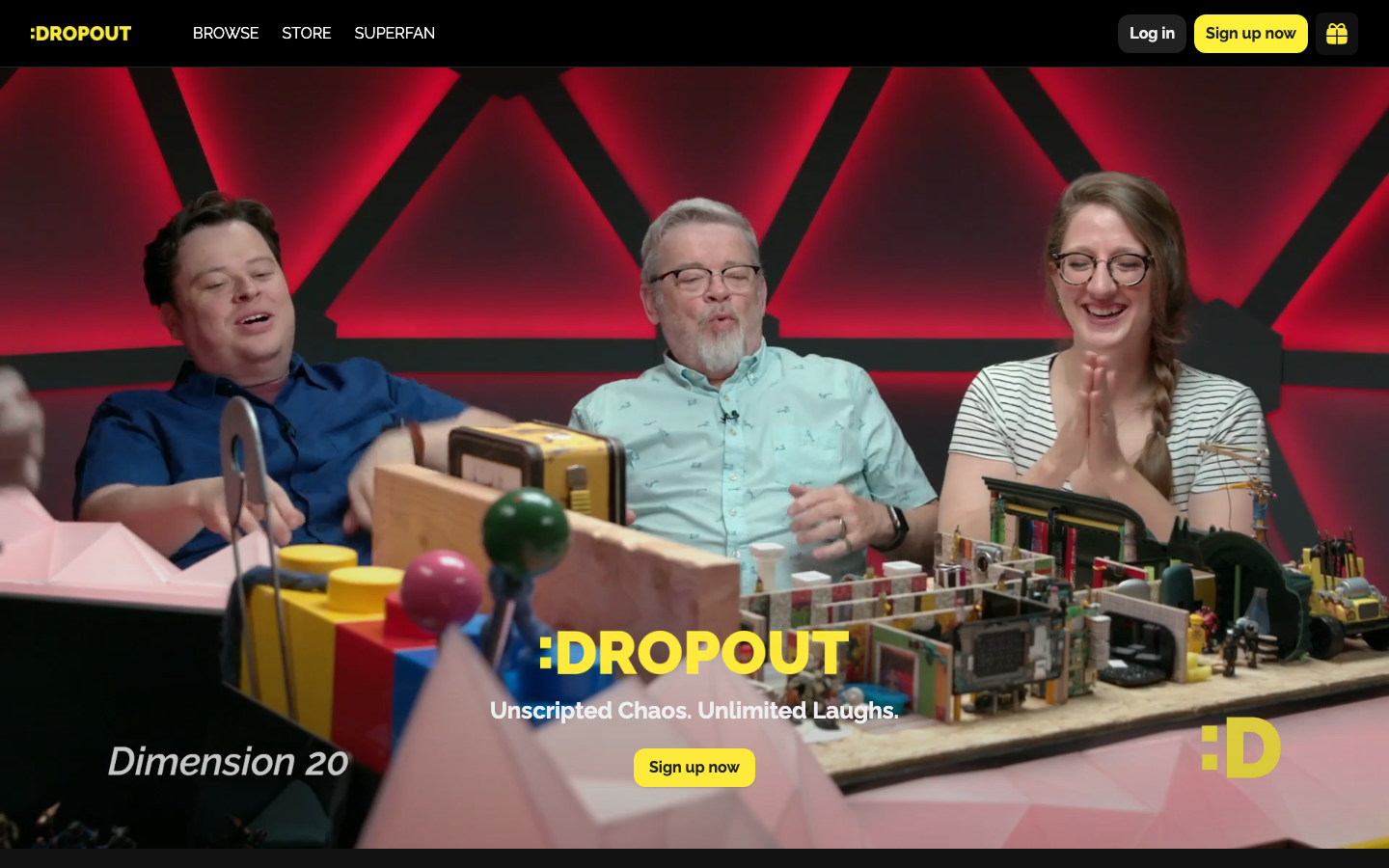 The composition is a dynamic split, with three figures in the foreground interacting with oversized, brightly colored toy blocks. The overall aesthetic feels deliberately chaotic and energetic, mirroring the show's premise. · comedy show, dropout tv, unscripted, talk show, colorful, toys, studio, podcast, interview